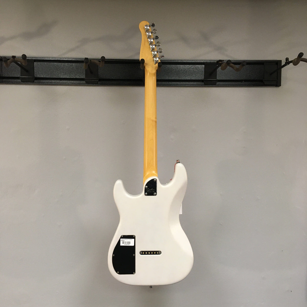 Godin Session HT Trans Cream RN electric guitar with a yellow handle, featuring a hardtail bridge and H-S-S pickup configuration, displayed on a wall.