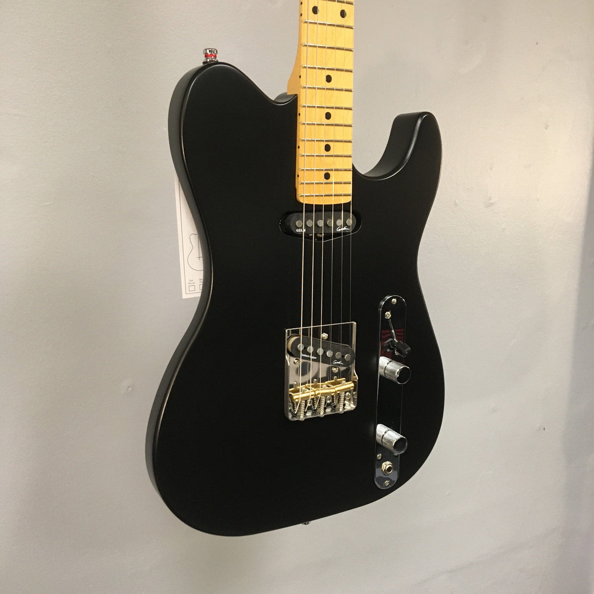 Godin Stadium HT Matte Black electric guitar with maple neck, single-cut body, and custom pickups, displayed on a wall.