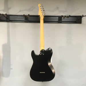 Godin Stadium HT Matte Black MN electric guitar with silver and gold accents, mounted on a wall.