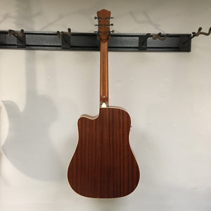 Luna Art Vintage Dreadnought Acoustic/Electric Guitar hanging on a wall, showcasing its rustic finish and solid-built construction.