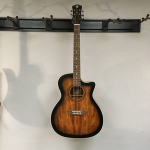 Luna Art Vintage Grand Auditorium Solid Top Cutaway A/E guitar mounted on a wall, showcasing its vintage brown burst finish and distinct rustic look.