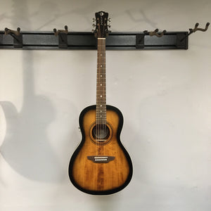 Luna Art Vintage Parlor Solid Top guitar with a distressed vintage brownburst finish, featuring a compact parlor body shape and open gear tuners.