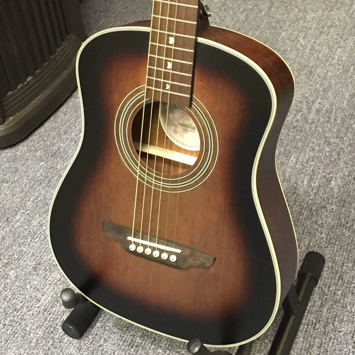 Luna Safari Artist Vintage Travel Guitar on a stand, featuring mahogany body, spruce top, and pearl moon phase inlays, with branded travel bag included.