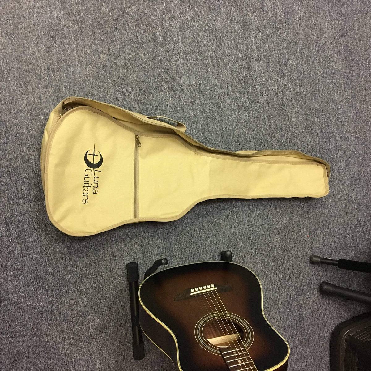 Luna Safari Artist Vintage Travel Guitar with gigbag, featuring a mahogany body, spruce top, and pearl moon phase inlays, placed on a carpet.