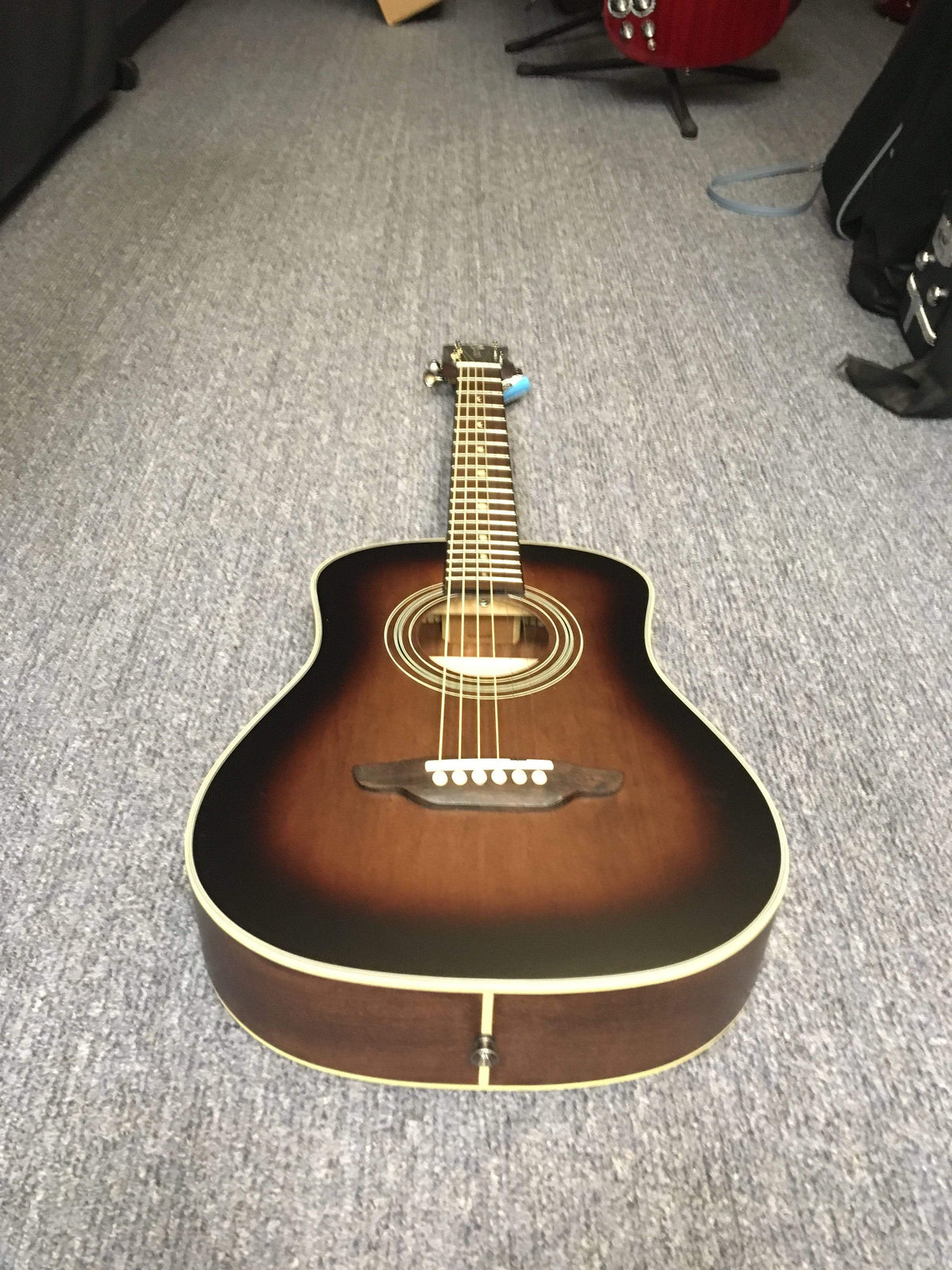 Luna Safari Artist Vintage Travel Guitar with Gigbag, featuring a mahogany body, spruce top, and pearl moon phase inlays, lying on a carpet.
