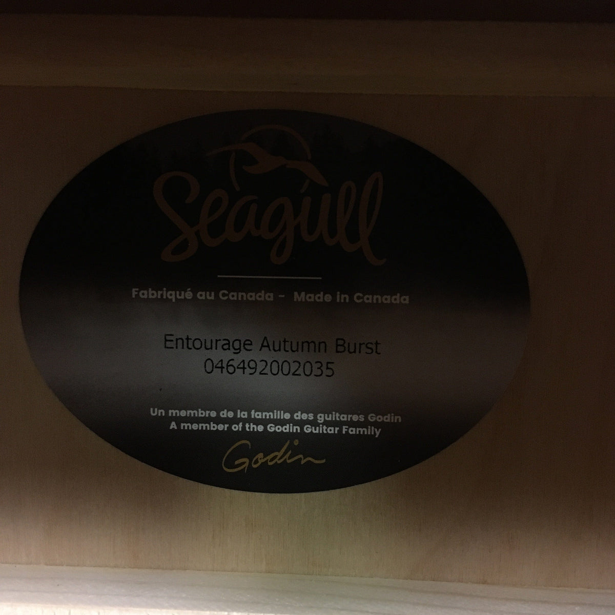 A close-up photo shows the Seagull Entourage Autumn Burst Acoustic Guitar label inside the body, featuring its model name and serial number, and stating it's made in Canada by Seagull.