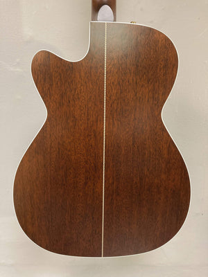 The image shows the back of a Seagull Artist Mosaic CH CW Acoustic-Electric Guitar - Bourbon Burst by Seagull, featuring a dark wood finish, white center inlay, and white binding, set against a plain light-colored wall.