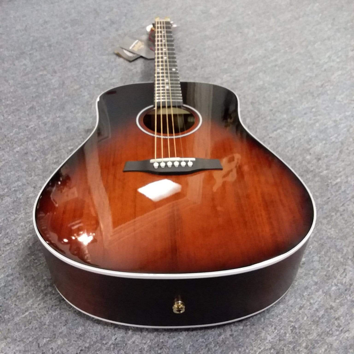Seagull Maritime SWS Mahogany Burnt Umber GT QIT Acoustic Guitar lying on a carpet, showcasing its detailed craftsmanship and elegant finish.