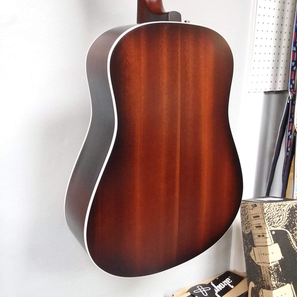 Seagull Maritime SWS Mahogany Burnt Umber GT QIT Acoustic Guitar hanging on a wall, showcasing its elegant design and craftsmanship.