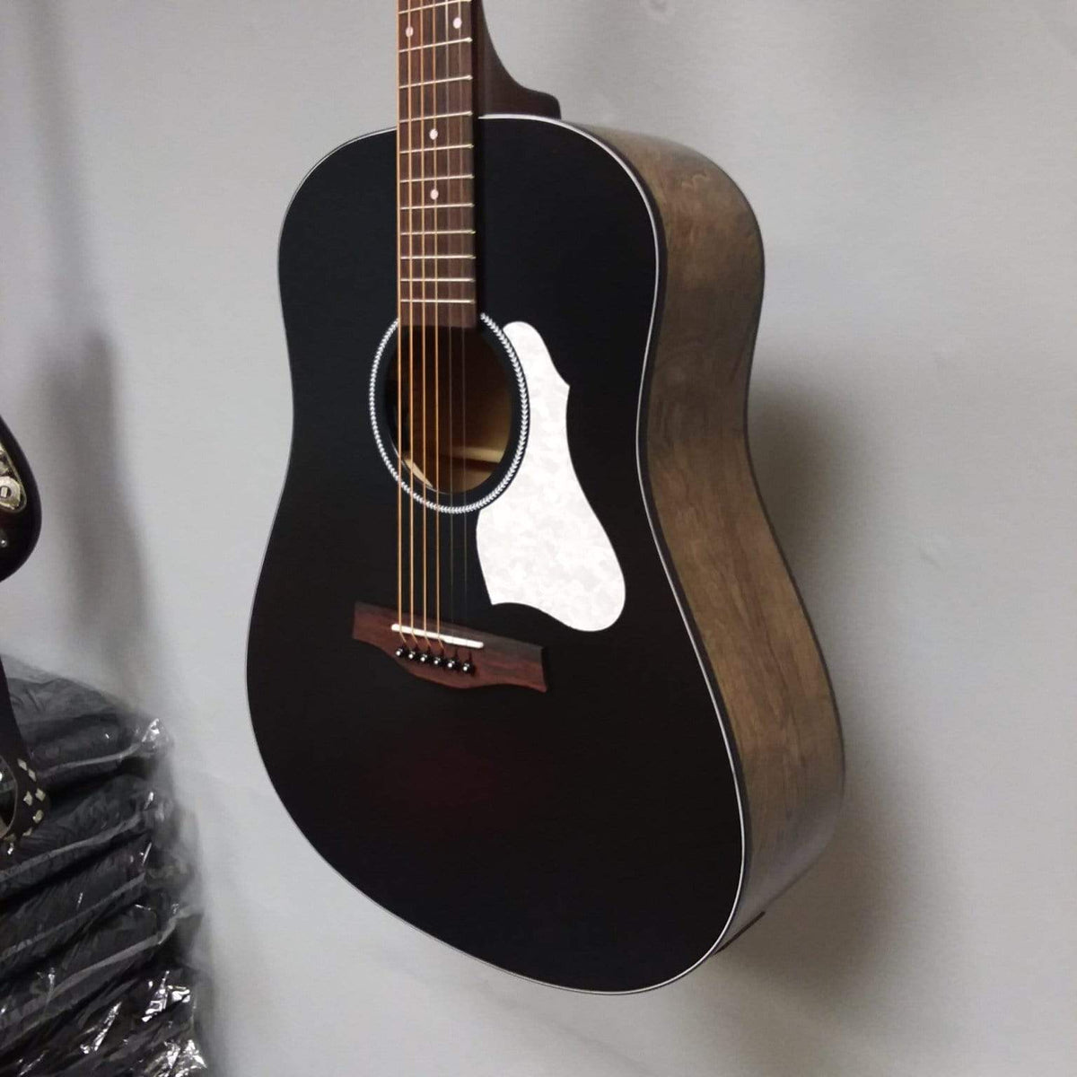Seagull S6 Classic A/E Black guitar mounted on a wall, showcasing its sleek design and robust build.