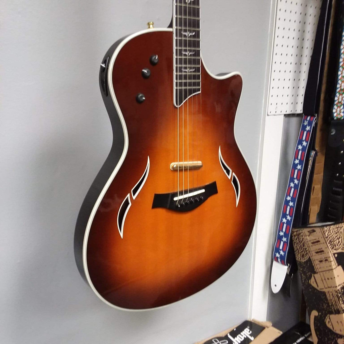 Taylor T5-C 2006 guitar with Custom Fishman Matrix Piezo pickup, hanging on a wall, showing visible wear, and comes with a case.