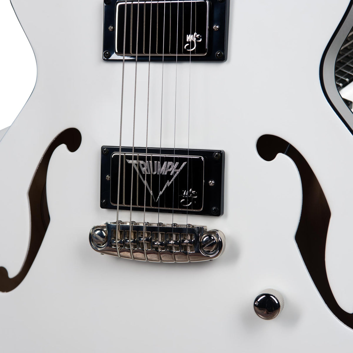 Close-up of a white Godin Rik Emmett Premiere Electric Guitar, showcasing chrome hardware, black "TRIUMPH" pickups, and distinctive f-hole cutouts—striking features from this limited edition Godin signature model.