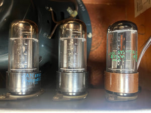 Three vacuum tubes are arranged side by side in the 1954 Fender Tweed Deluxe Model 5D3 by Guitars on Main, each displaying labels and metal bases reminiscent of classic hand-wired amplifiers.
