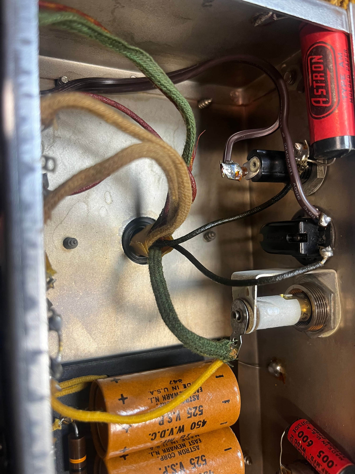 Close-up view of vintage electronic components and wiring, including a red Astron capacitor, inside a hand-wired 1954 Fender Tweed Deluxe Model 5D3 w/Flight Case by Guitars on Main.