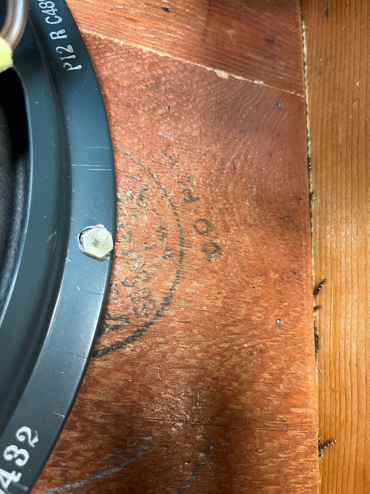 Close-up of a metal speaker frame bolted to wood in a 1954 Fender Tweed Deluxe Model 5D3 by Guitars on Main, featuring partially visible "40 P" black stamped text and other faded markings.