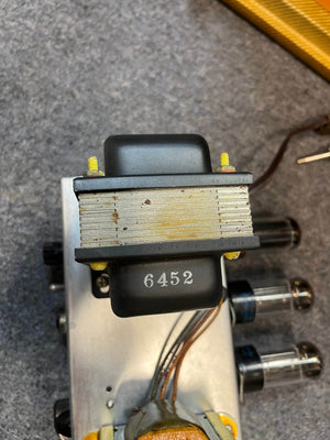 Close-up of a metal transformer marked 6452, mounted on a vintage Guitars on Main 1954 Fender Tweed Deluxe Model 5D3 tube amplifier chassis with visible wires and vacuum tubes, sold with flight case.