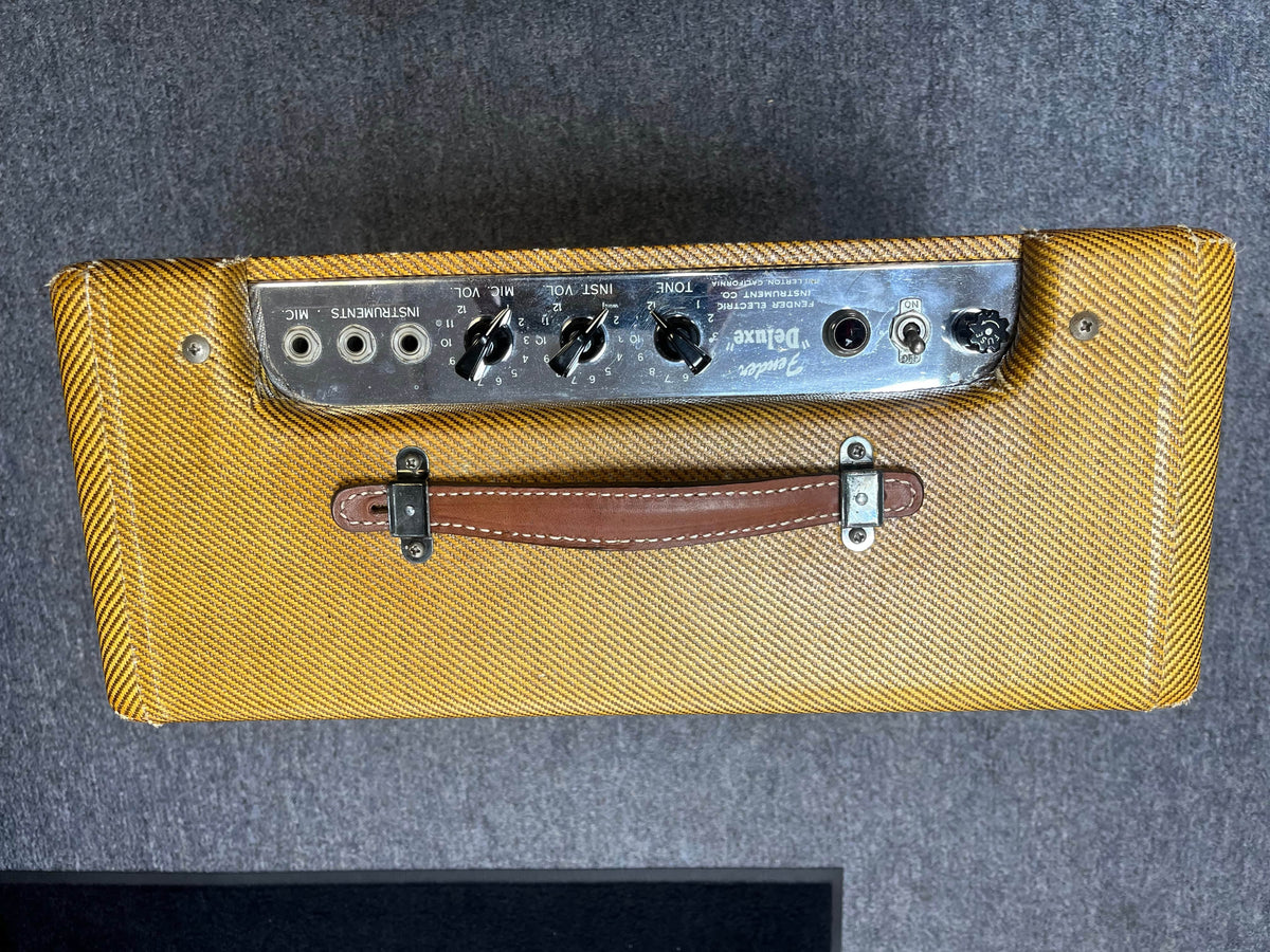 Top view of a 1954 Fender Tweed Deluxe Model 5D3 by Guitars on Main, featuring a brown leather handle, yellow tweed covering, and exposed control knobs and input jacks. Includes flight case.