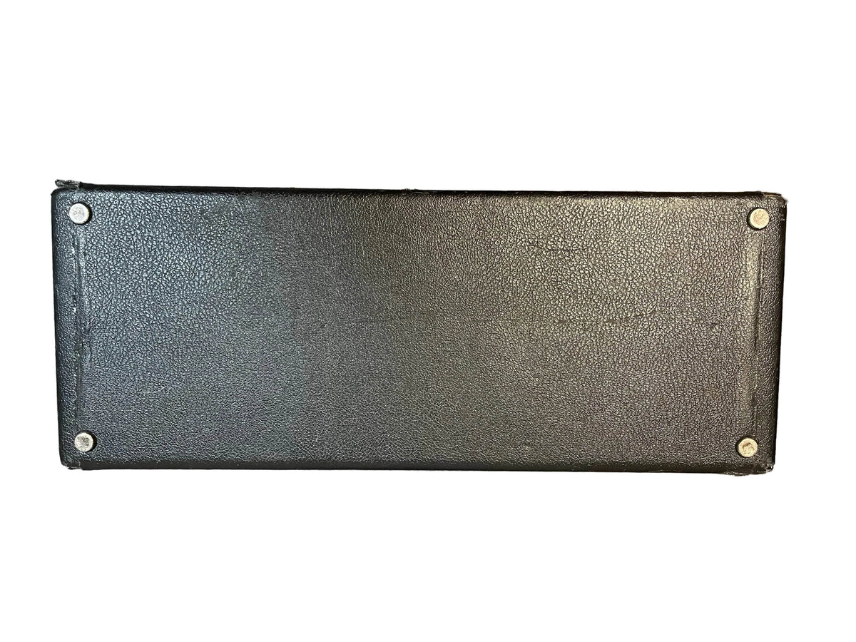 The Fender 1965 Deluxe Reverb AB763 (Pre-CBS Blackface, Serial A 06439) features a rectangular black textured design with four metal screws at each corner, echoing the iconic look of classic Fender amps against a white background.
