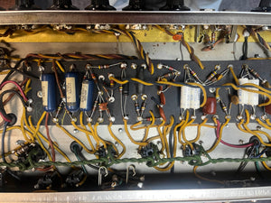 Close-up of components and wiring inside an open metal enclosure of a 1965 Fender Deluxe Reverb AB763 Pre-CBS Blackface (serial A 06439), showing capacitors, resistors, and wires on terminal strips.