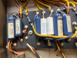 Close-up of electronic components—blue capacitors, resistors, wires, and a screw—on a vintage Fender 1965 Deluxe Reverb AB763 Pre-CBS Blackface amp (Serial A 06439).