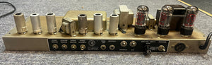 Rear view of a Fender 1965 Deluxe Reverb AB763 Pre-CBS Blackface (Serial A 06439) shows vacuum tubes, transformers, and input/output jacks on a grey carpet—classic vintage amp details.
