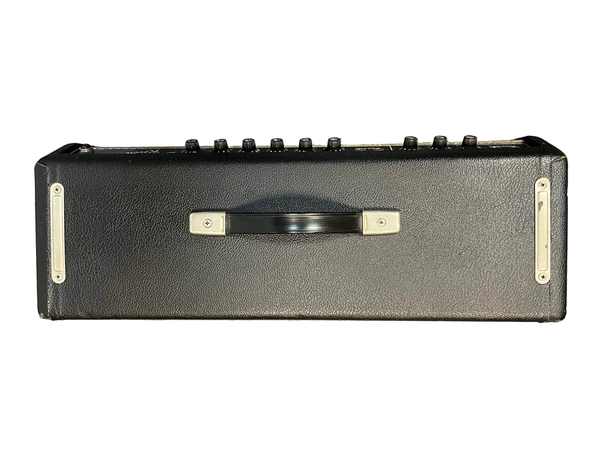 A top-down view of a 1965 Fender Deluxe Reverb AB763 Blackface amp head, with a central handle and control knobs along the top, evokes the classic Pre-CBS Fender style. Serial A 06439.