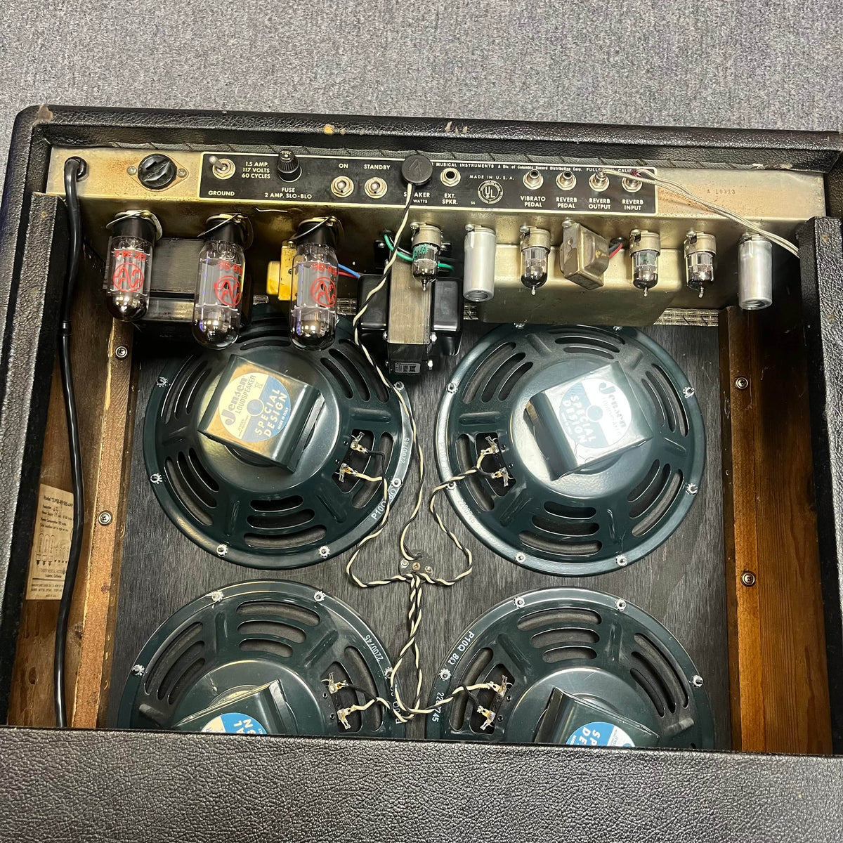 A close-up of a 1965 Fender Super Reverb - Black Panel from Guitars on Main shows four speakers, vacuum tubes, and wiring—capturing the essence of classic Black Panel sound. Available for local pickup.