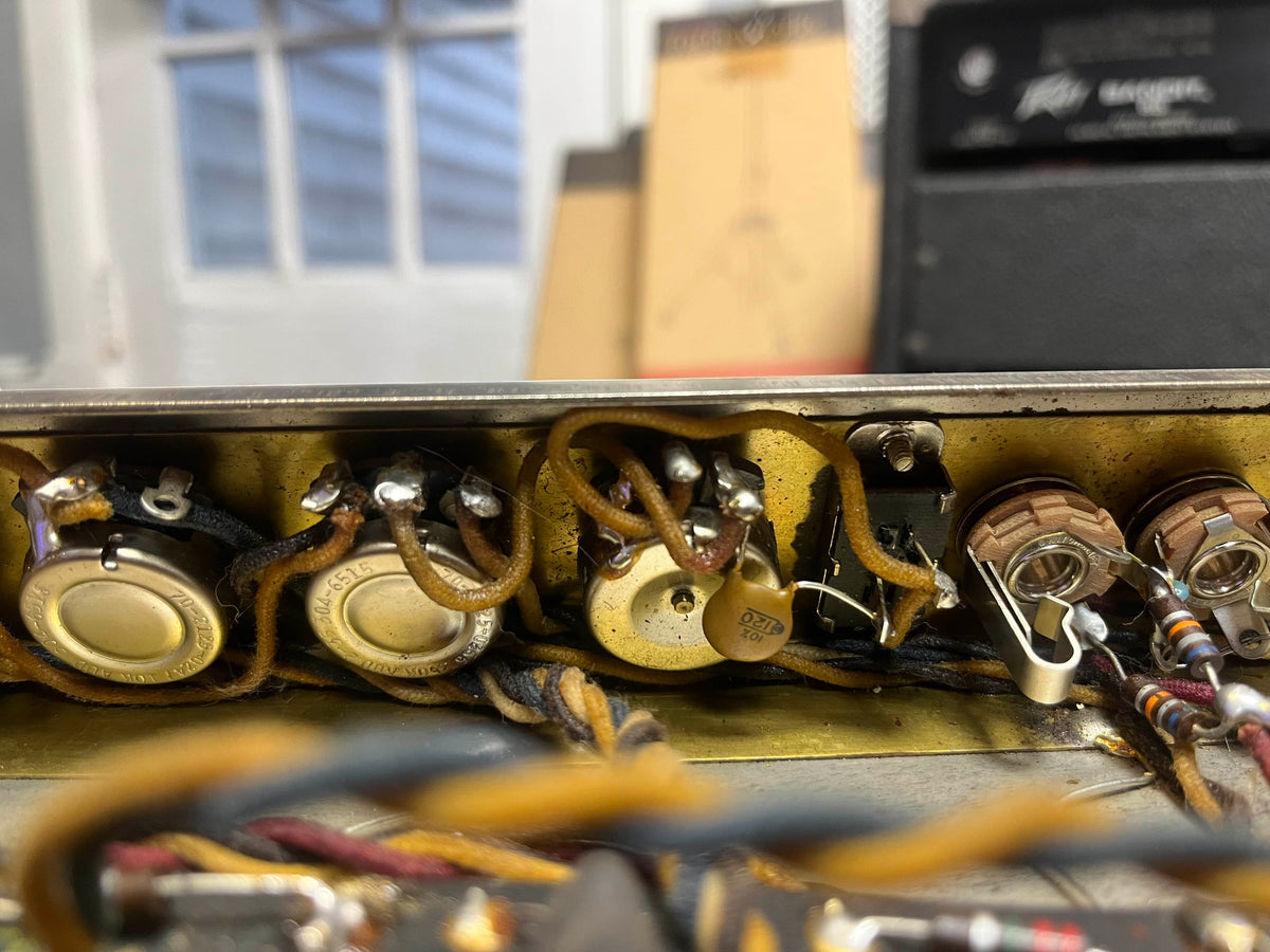 Close-up of vintage electronic components and wiring inside a metal enclosure from a 1965 Fender Super Reverb - Black Panel - "Player’s Dream" Restoration, offered by Guitars on Main.