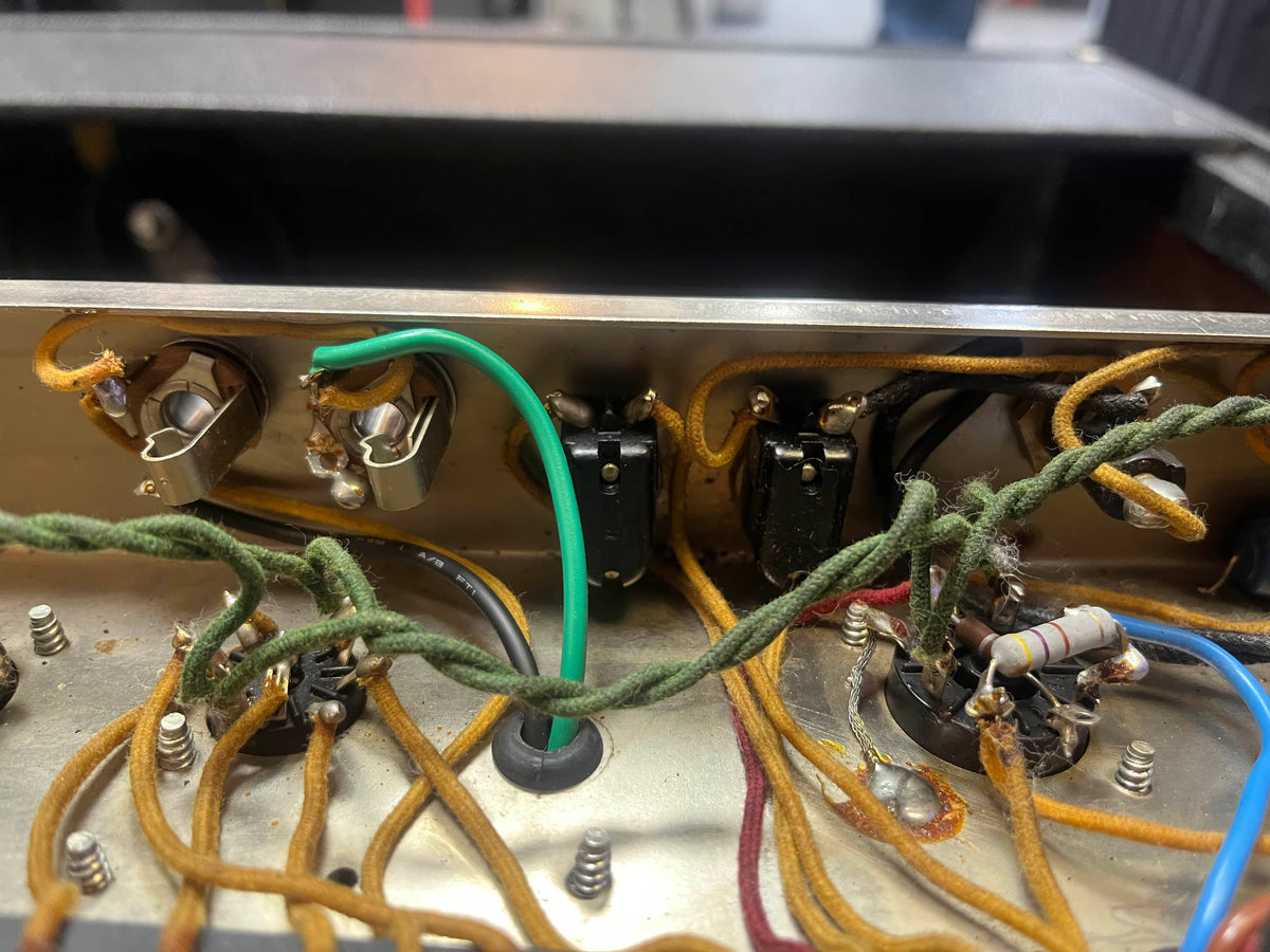 Detailed view of the internal wiring and components of a 1965 Fender Super Reverb - Black Panel, restored by Guitars on Main—showing classic colored wires, screws, and resistors that create its iconic “Player’s Dream” sound.