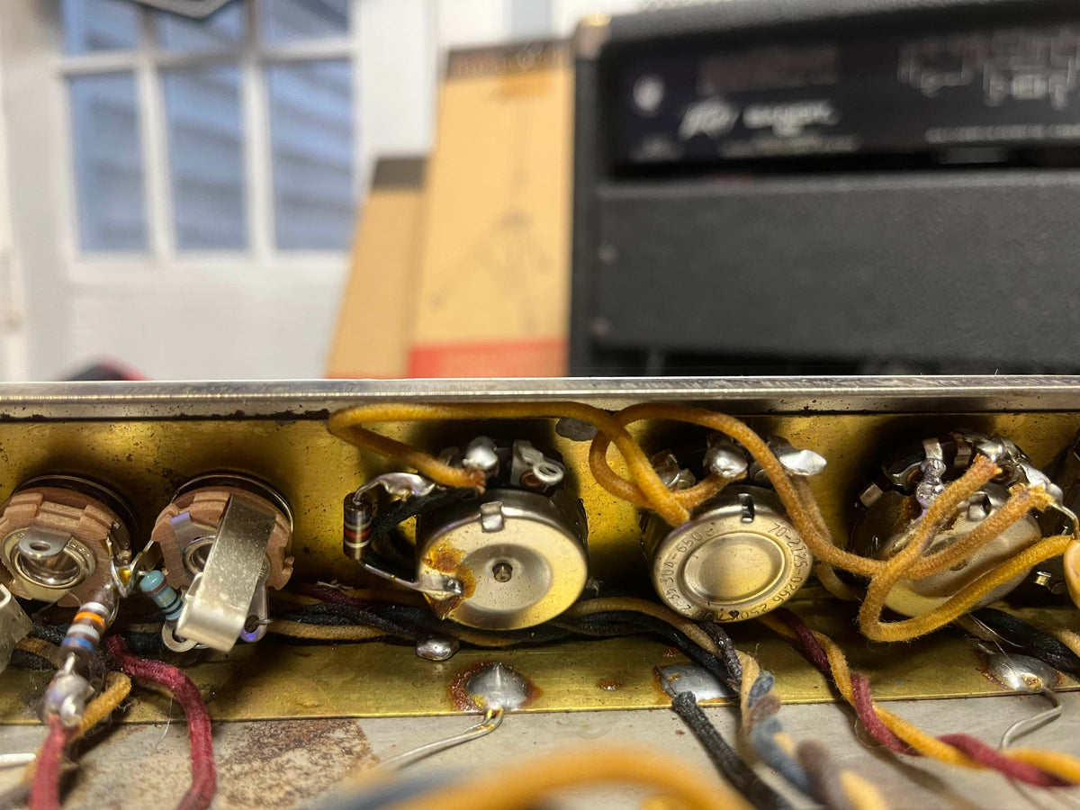Close-up of vintage electronic components and wiring inside a 1965 Fender Super Reverb - Black Panel, available for local pickup from Guitars on Main, highlighting potentiometers and resistors that deliver its classic tone.