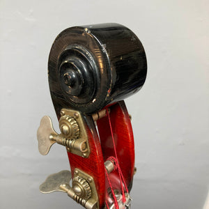 Close-up of the scroll and tuning pegs on an Ampeg 1966 ASB-1 Devil Bass (Serial #531), featuring red varnish and metal hardware reminiscent of a vintage upright, set against a plain gray background.