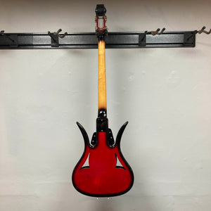 A striking red 1966 Ampeg ASB-1 Devil Bass (Serial #531), featuring a natural wood neck, hangs backward on a black wall-mounted rack to showcase the back of its body and neck, echoing the distinctive vintage design that defines this iconic Ampeg model.
