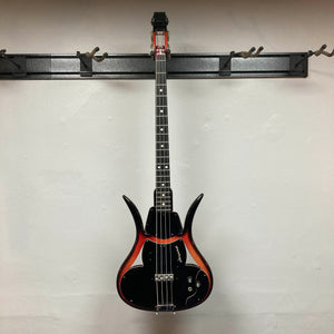 Ampeg 1966 ASB-1 Devil Bass (Serial #531) with a red and black sunburst finish, evoking vintage style, displayed on a wall-mounted rack against a plain white wall. This model features a bridge-mounted transducer pickup, true to the iconic Ampeg ASB-1 Devil Bass design. Includes case.