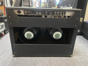 The back of a 1966 Fender Twin Reverb 2-Channel 85-Watt 2x12" Guitar Combo Amp w/Flight Case shows twin speakers, control panel with jacks and knobs, tubes, and spring reverb displayed inside a music equipment store.