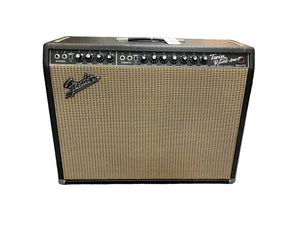 A 1966 Fender Twin Reverb 2-Channel 85-Watt 2x12" Guitar Combo Amp by Fender, featuring spring reverb, multiple controls, switches, and a brown woven grille, shown with a flight case against a white background.