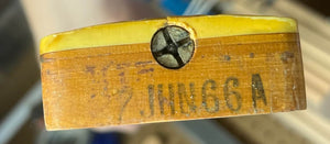 Close-up of a wooden part with a yellow top and metal screw, showing faded "JINNGG A" text—likely an original pickup from a Fender 1966 Jazz Bass Natural Refinish w/Case.