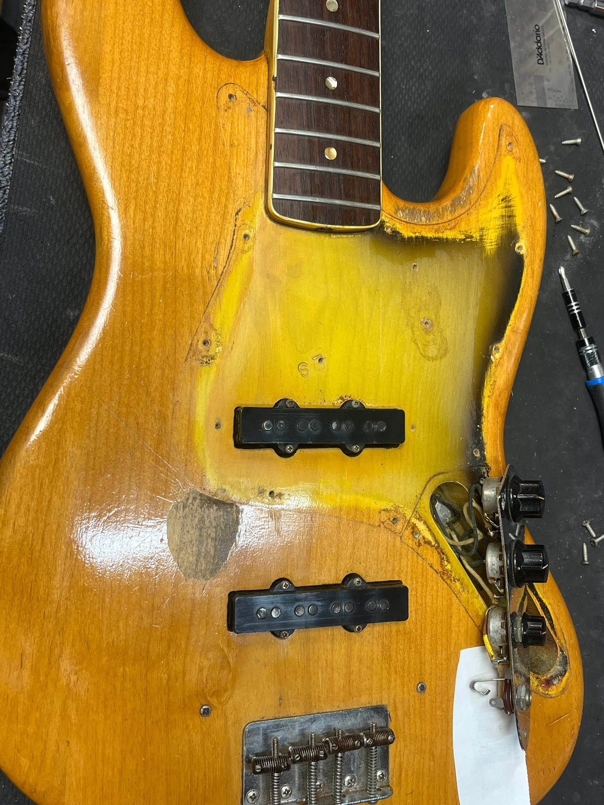 A 1966 Fender Jazz Bass Natural Refinish by Fender, featuring original exposed pickups, intact control knobs, missing pickguard, and visible wear—classic vintage character. Includes case.
