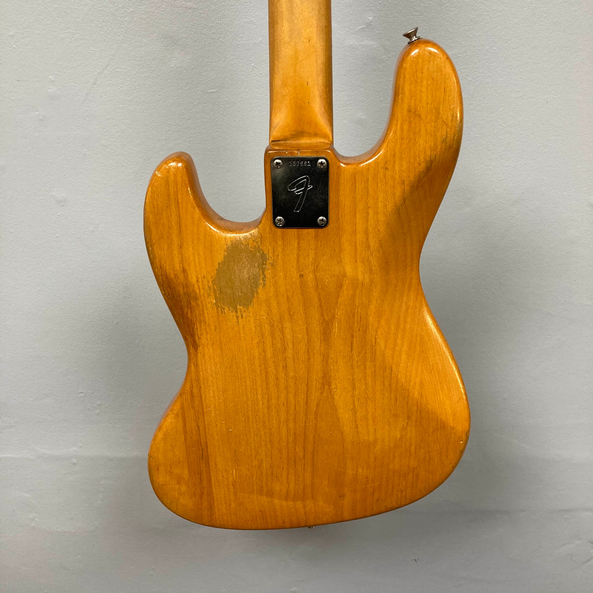 The back of a 1966 Fender Jazz Bass Natural Refinish w/Case by Fender, featuring a metal neck plate and visible wear on the finish.