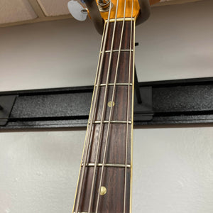 Close-up of a 1966 Fender Jazz Bass Natural Refinish neck and fretboard, showing metal frets, dot inlays, and part of the headstock against a white wall. Includes case.