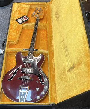 A vintage 1967-68 Vox Sidewinder IV Bass (V272) Cherry by Vox is displayed in an open hard case lined with yellow velvet.