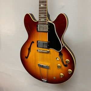 1967 Gibson ES-335 Sunburst electric guitar, semi-hollow body with vintage sunburst finish, close-up on strings and dials, comes with a protective case.