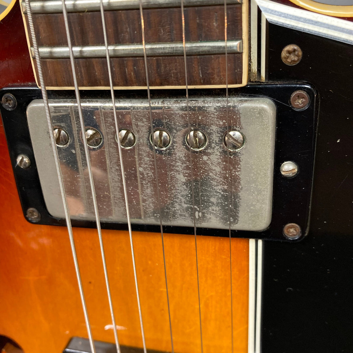 Close-up of 1967 Gibson ES-335 Sunburst guitar strings and screws.