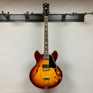 1967 Gibson ES-335 Sunburst on a stand, showcasing its semi-hollow body design and classic sunburst finish. Comes with a protective case.