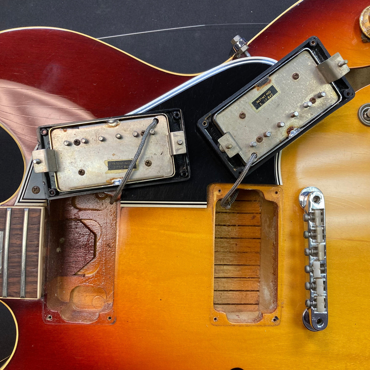 Close-up of a 1967 Gibson ES-335 Sunburst electric guitar with visible screws, strings, and a protective case.