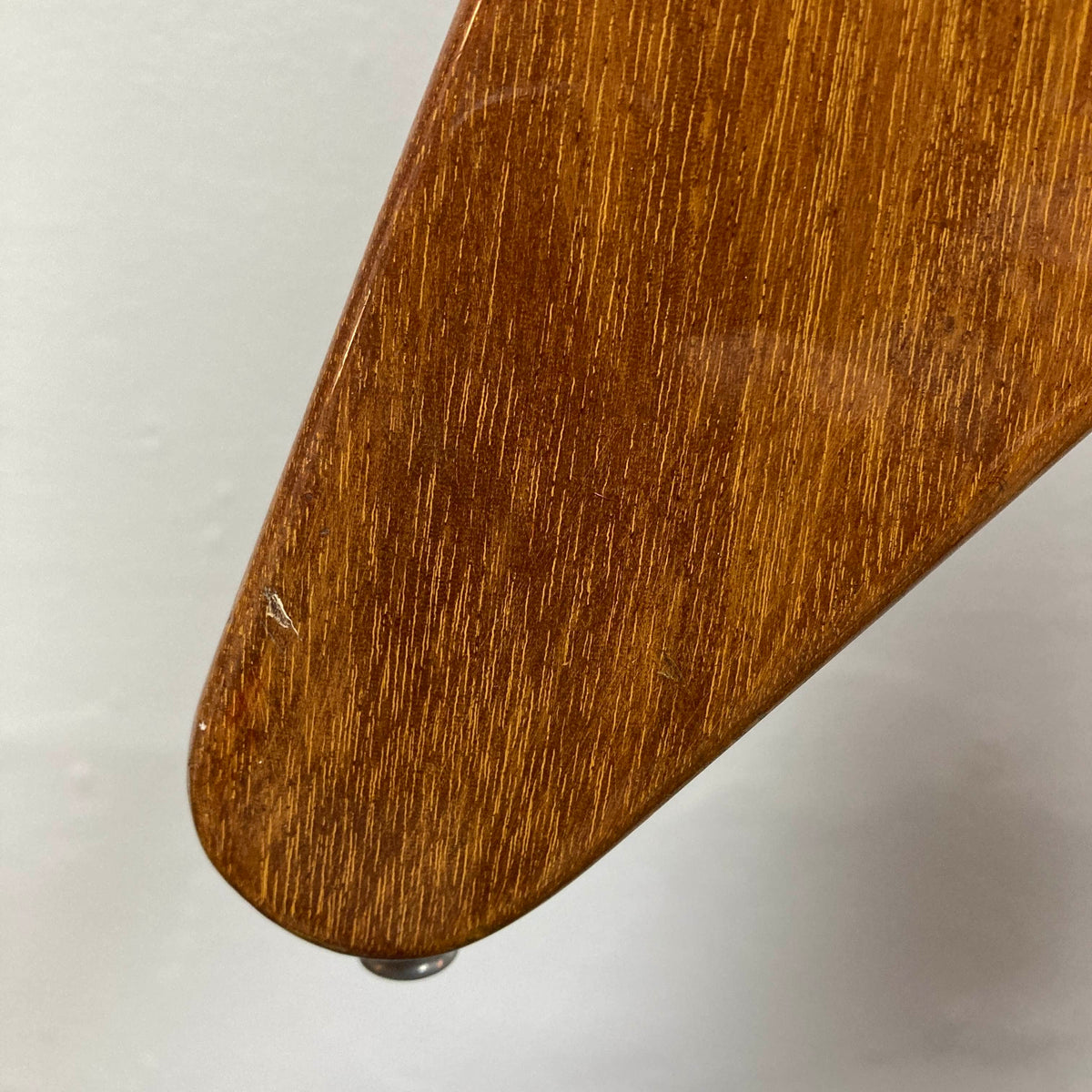Close-up of a wooden furniture leg featuring a natural finish and glossy sheen, highlighting minor scratches and detailed wood grain reminiscent of the character found in a vintage 1975 Gibson Flying V w/Case by Gibson, set against a plain background.