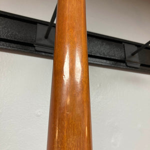 Close-up of the neck of a 1975 Gibson Flying V w/Case by Gibson, featuring a natural wood finish with visible indentations and minor scratches. Displayed against a white wall and black metal wall hanger, the wear enhances the vintage character distinctive to this classic instrument.