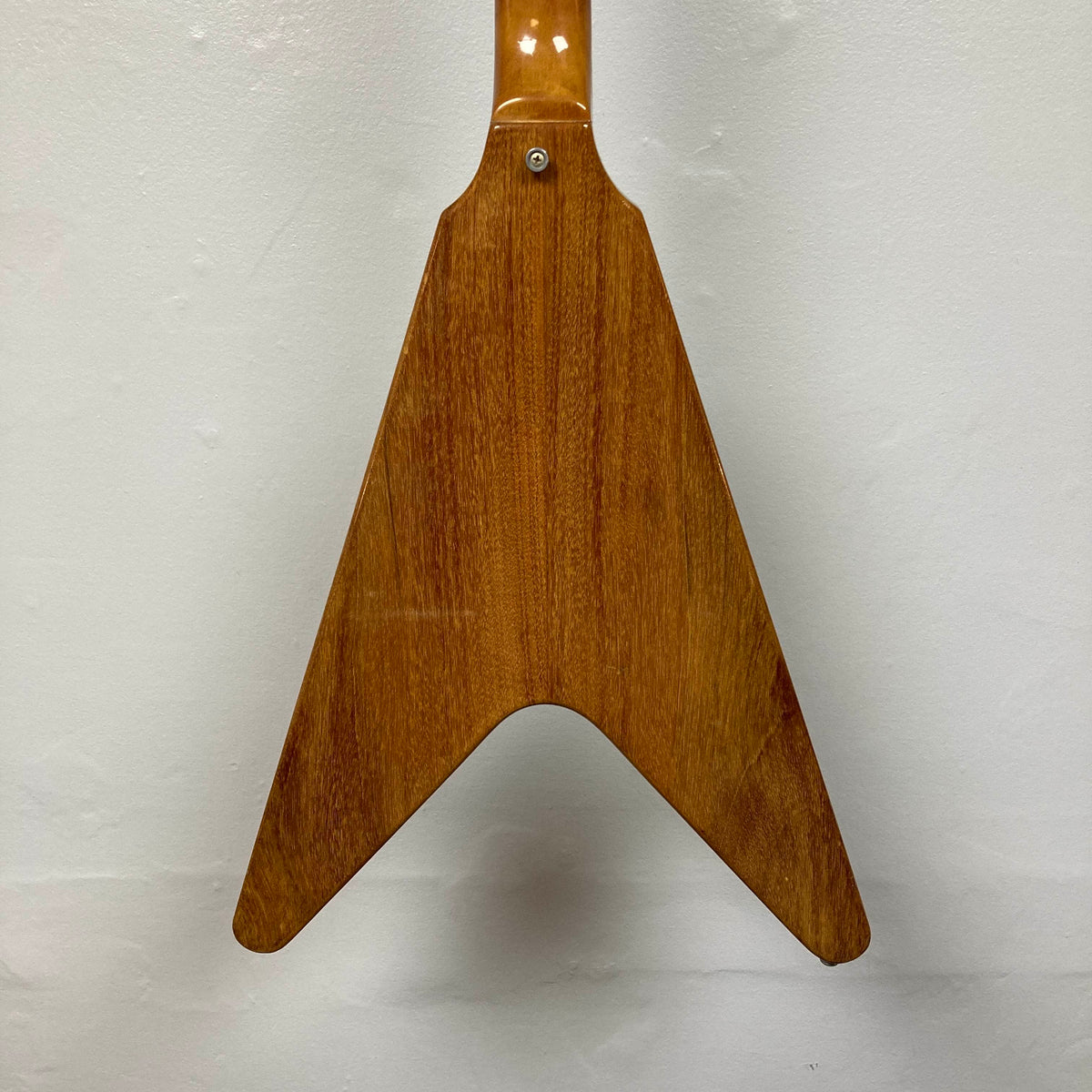 Back view of a 1975 Gibson Flying V electric guitar body with a distinctive V-shaped design, reminiscent of vintage models, showcased against a plain white background.