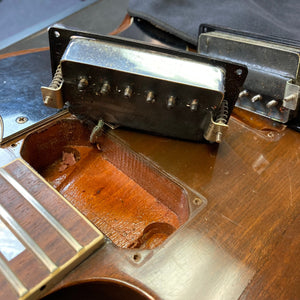 Close-up of a 1975 Gibson SG Standard Walnut electric guitar with visible tuning machines and fretboard inlays.