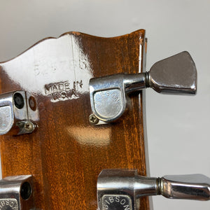 Close-up of a 1975 Gibson SG Standard Walnut guitar, highlighting its beveled Honduran Mahogany body and Mother of Pearl inlays.