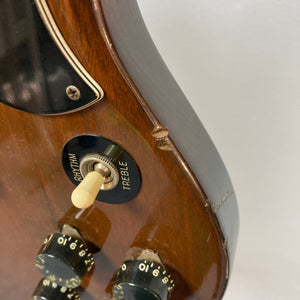 Close-up of a 1975 Gibson SG Standard Walnut guitar, featuring a solid mahogany body, T-Top pickups, and a beveled edge design.